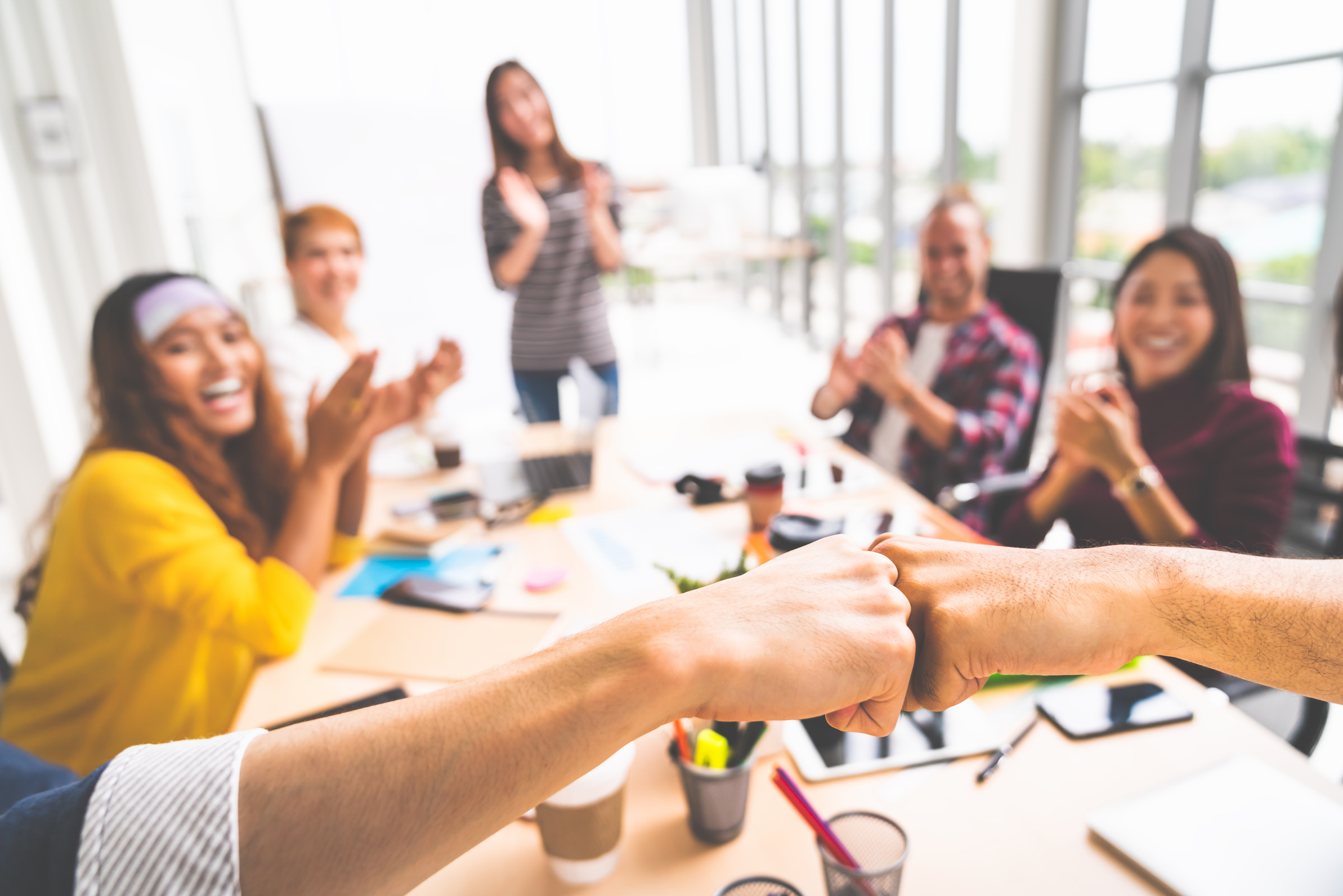 Business partners or coworkers fist bump in team meeting, multiethnic diverse group of happy colleagues clapping hands. Teamwork cooperation, team building, or success business project concept