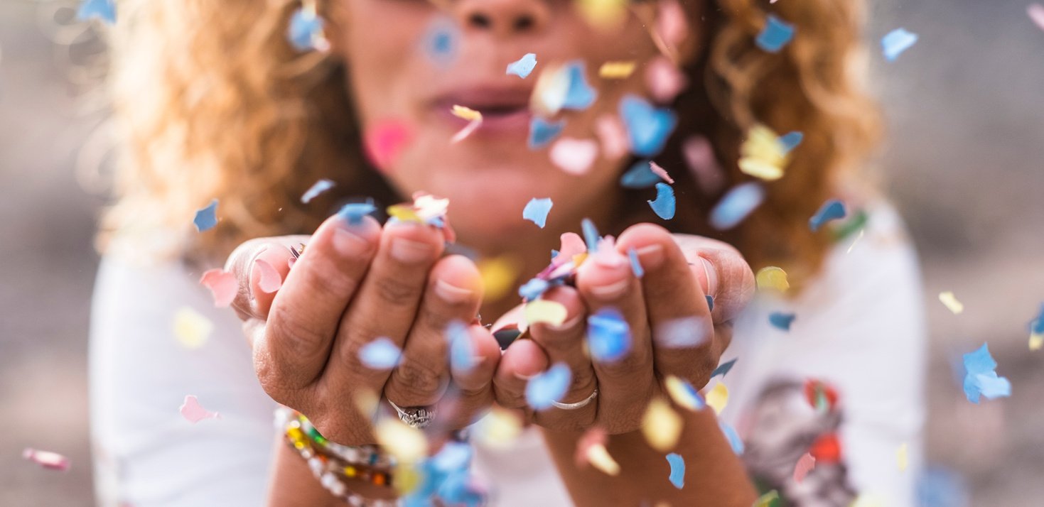 beautiful defocused woman blow confetti from hands. celebration and event concept. happiness and colored image. movement and happiness having fun